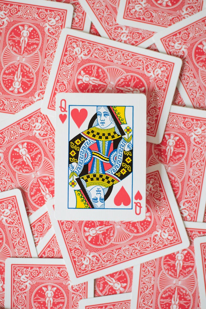 Close-up of Queen of Hearts surrounded by scattered red back playing cards.