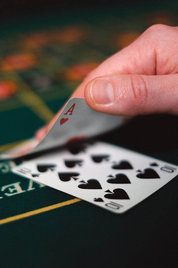 Tense moment in a casino with a hand revealing a winning card on a table.